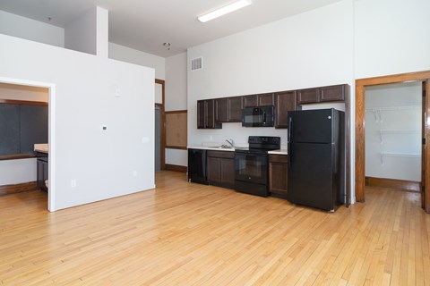 A kitchen with black appliances and wooden floors.