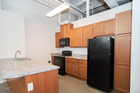 A kitchen with black appliances and wooden cabinets.