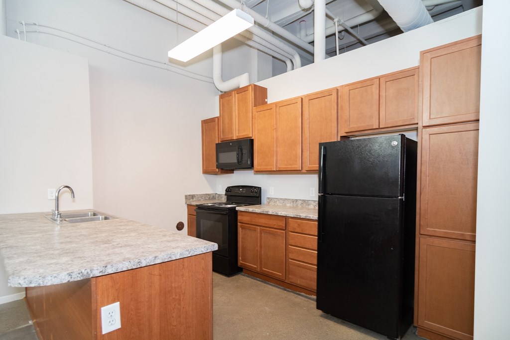 A kitchen with black appliances and wooden cabinets.