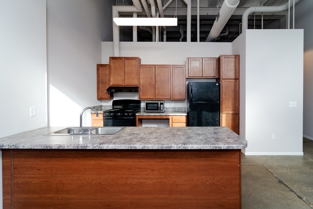 A kitchen with a granite countertop and wooden cabinets.
