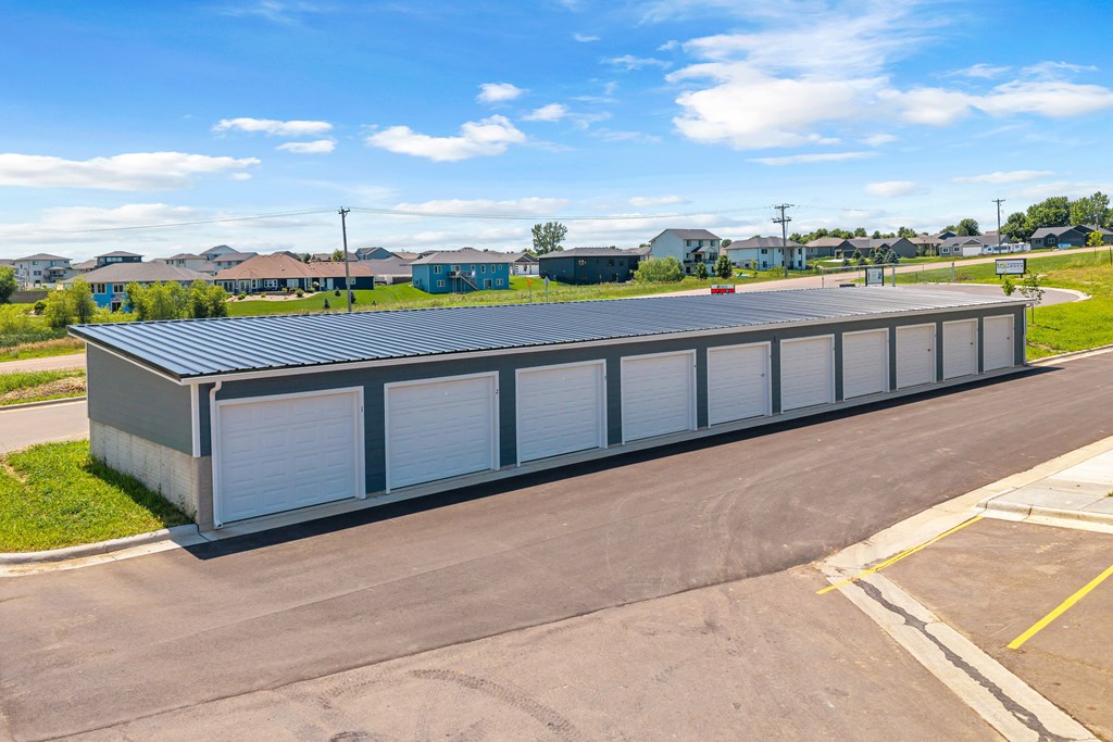 A large grey building with a metal roof and white garage doors.