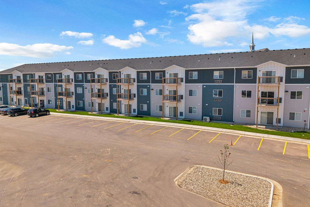 A parking lot in front of a large apartment complex.