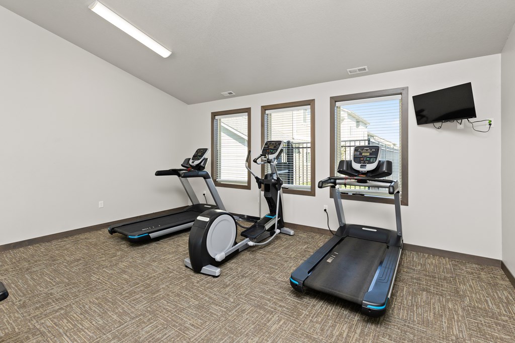 A room with a treadmill, elliptical trainer and a stationary bike.