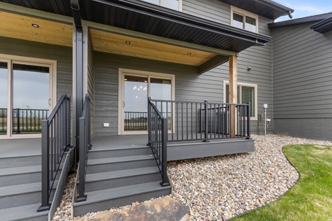 A modern house with a grey exterior and a black metal railing on the stairs.