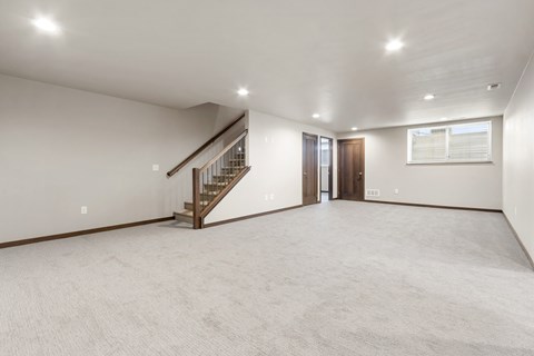 A spacious room with a staircase and a window.