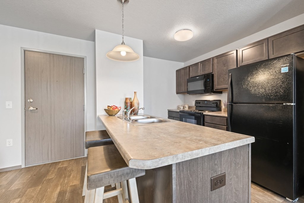 a kitchen with a large island and a black refrigerator
