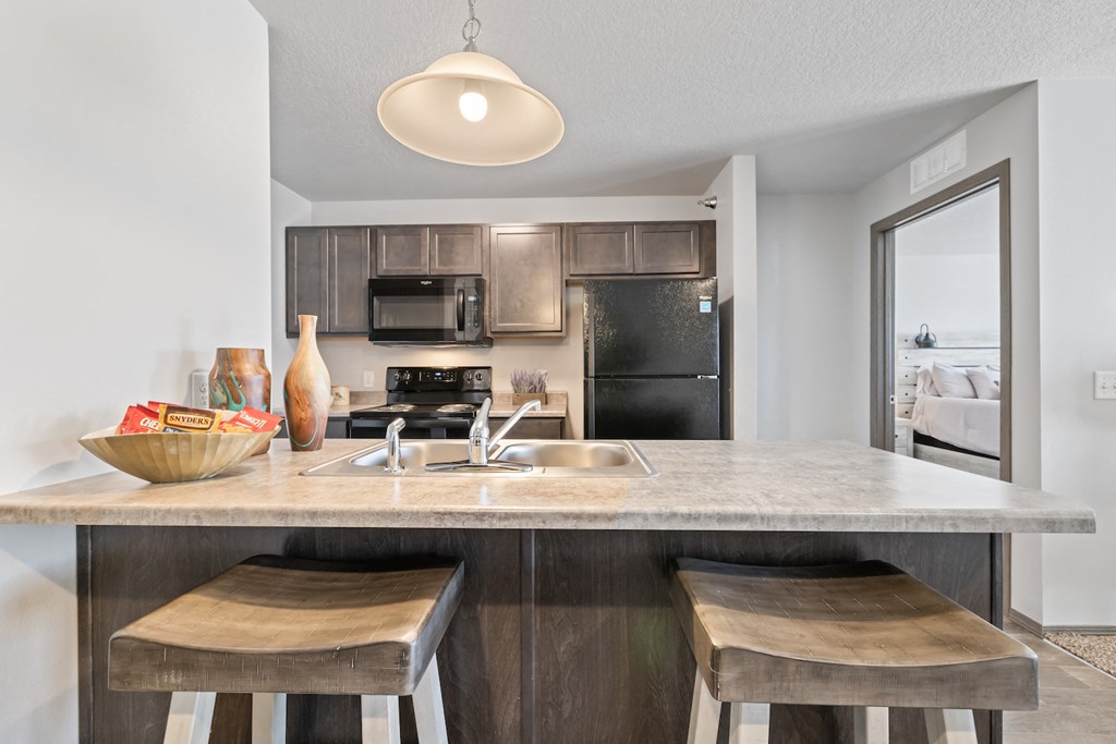 a kitchen with a sink and a counter top with two stools