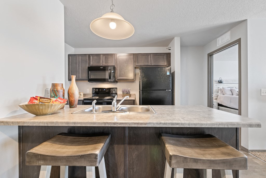 a kitchen with a sink and a counter top with two stools