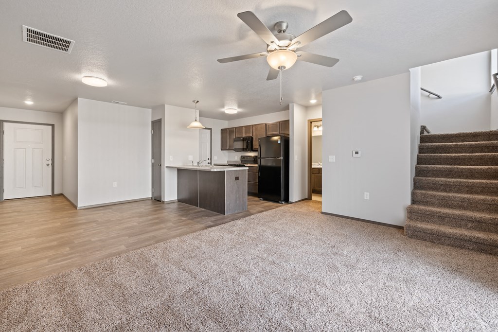 a living room with stairs and a ceiling fan