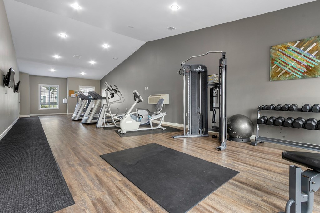 A gym with a variety of equipment including weights and a bench.