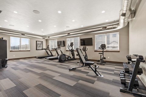 A gym with a variety of equipment including treadmills, weights, and exercise machines.