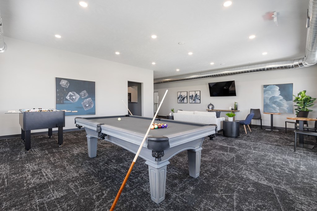 A pool table in a room with a chair and a plant.