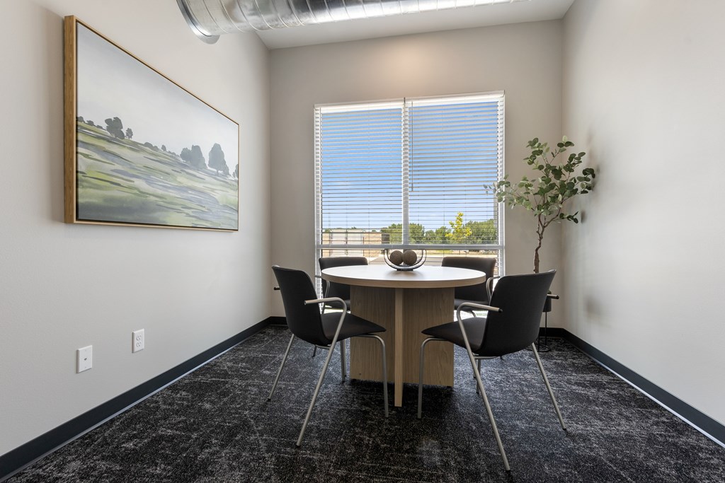 A room with a table, chairs and a painting on the wall.