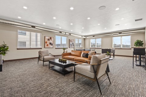 A spacious living room with a grey carpet and a brown sofa.