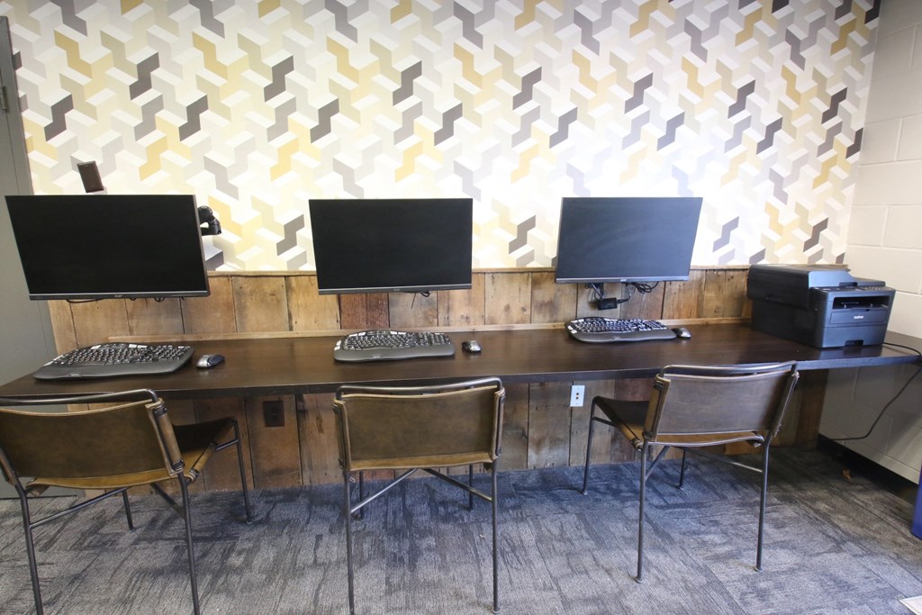 a computer room with three monitors on a wooden desk