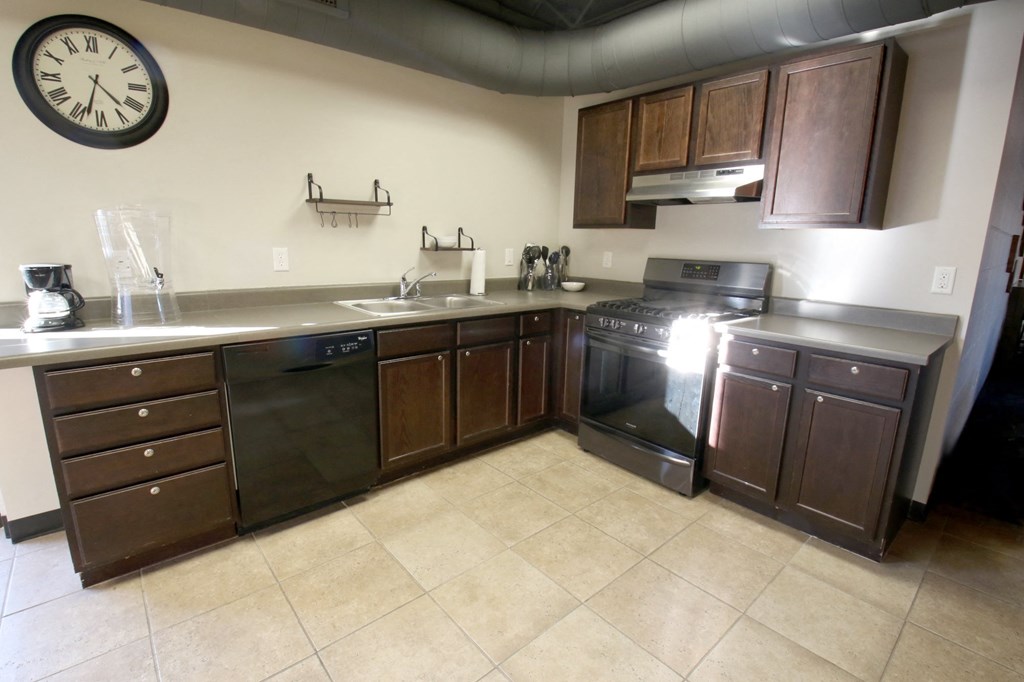 a kitchen with a clock on the wall and wooden cabinets