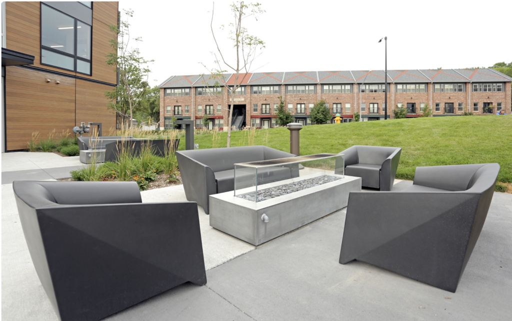 a patio with chairs and a fire pit in front of a building