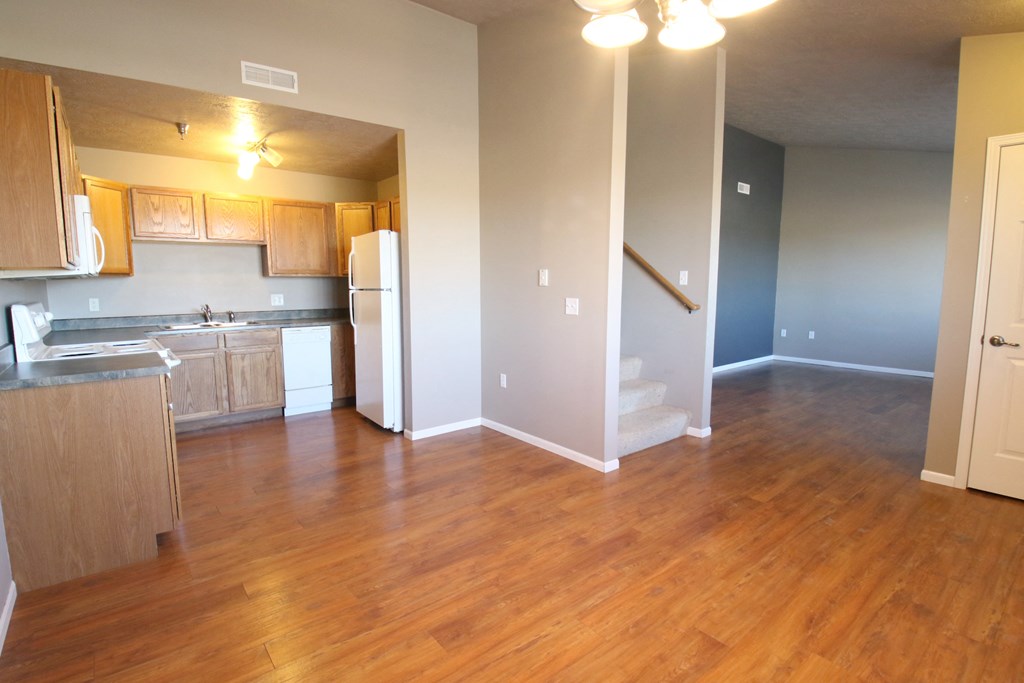 an empty living room and kitchen with wood flooring