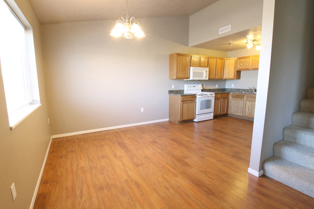 an empty living room and kitchen with wood flooring