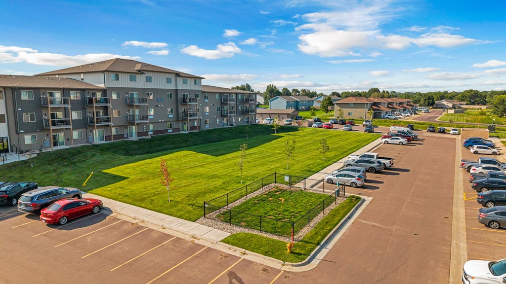 A parking lot with cars and a grassy area in front of a building.