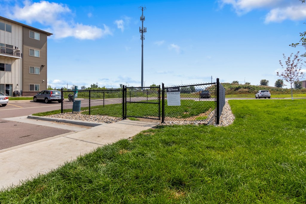 A sign is posted on a fence in front of a grassy area.