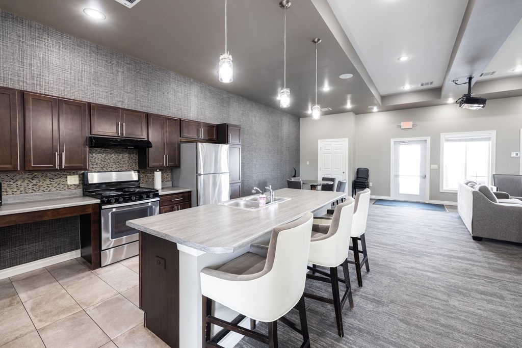 A modern kitchen with a large island and white chairs.