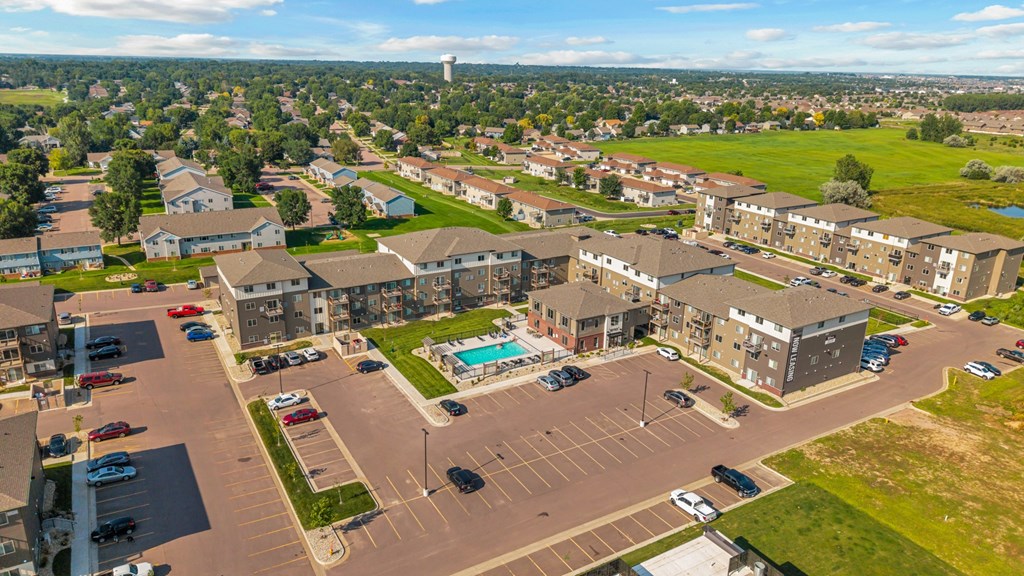 A large parking lot is surrounded by apartment buildings.