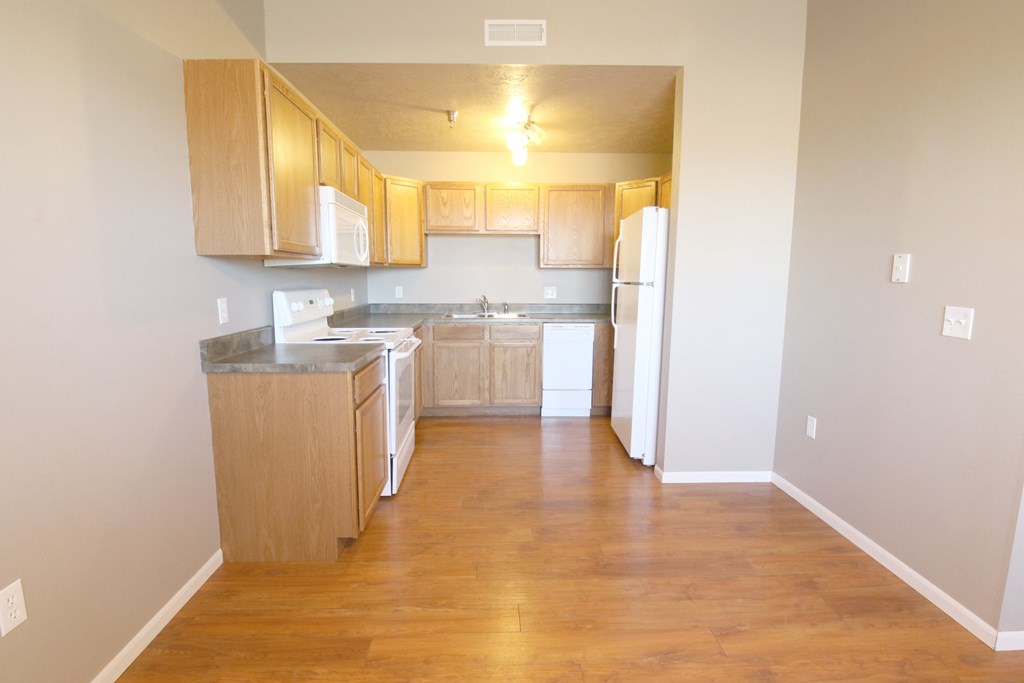 an empty kitchen with wood floors and wooden cabinets