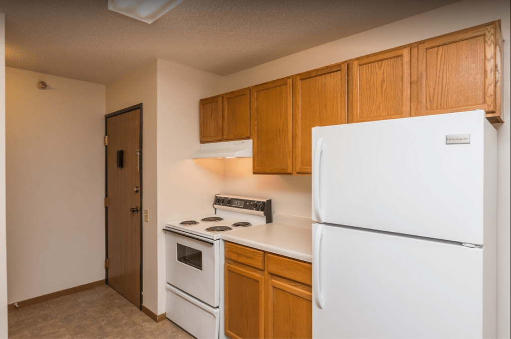 a kitchen with white appliances and wooden cabinets and a refrigerator