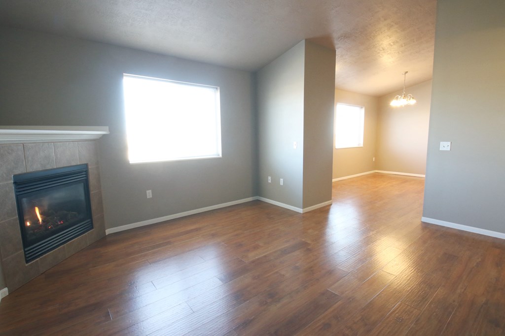 an empty living room with a fireplace and wooden floors