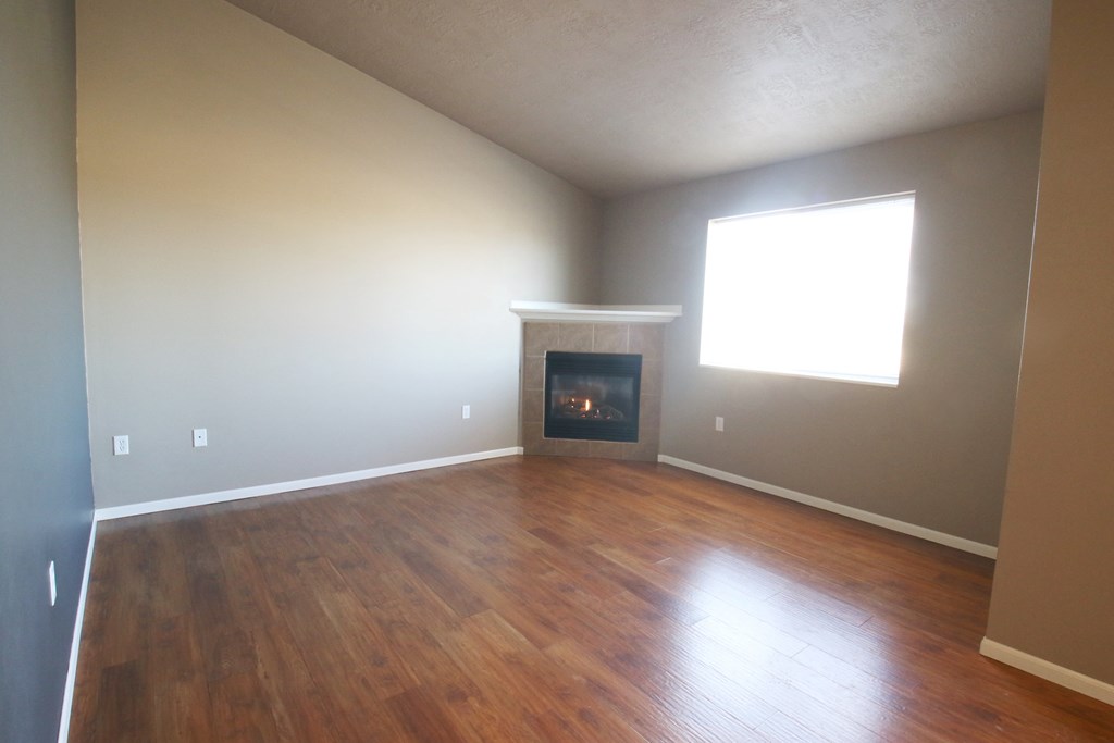 an empty living room with wood floors and a fireplace