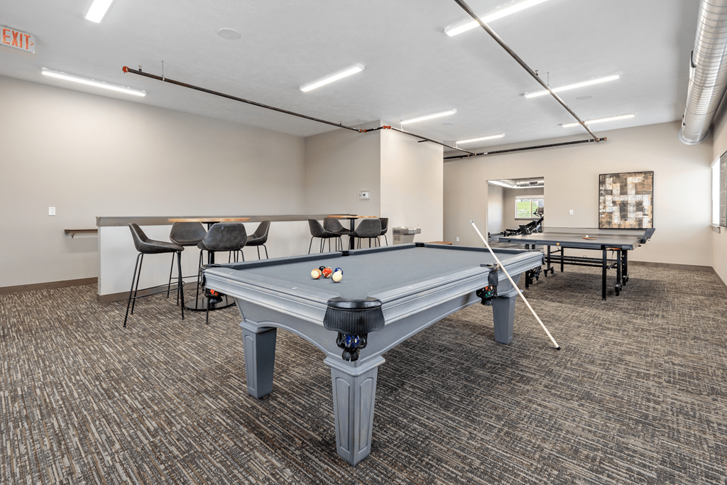 A pool table in a room with a carpeted floor and a white ceiling.