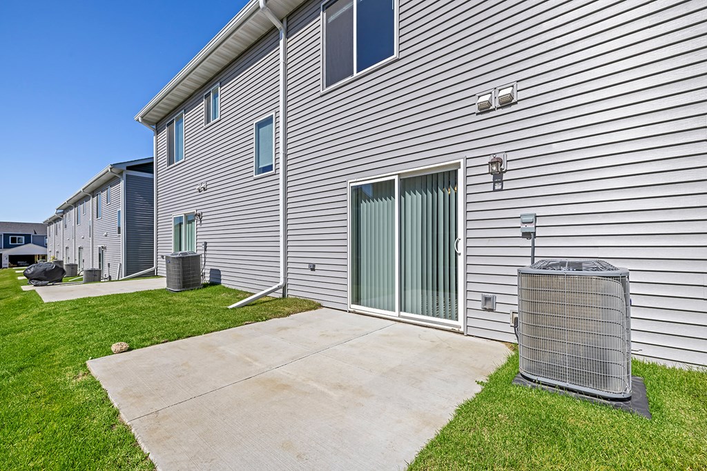 the yard of a house with a patio and a trash can