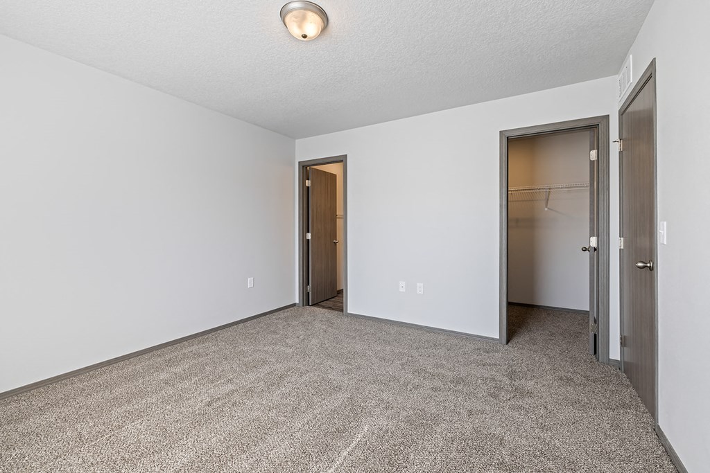an empty living room with a closet and a door to a hallway