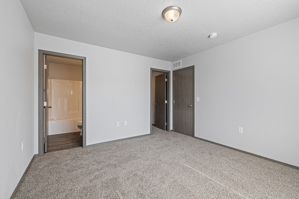 Bright, vacant bedroom with neutral walls and carpet flooring.