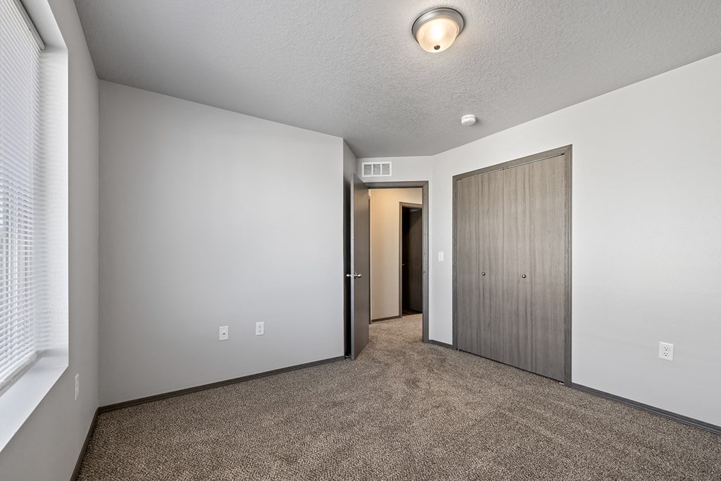 Bright, vacant bedroom with neutral walls and carpet flooring.
