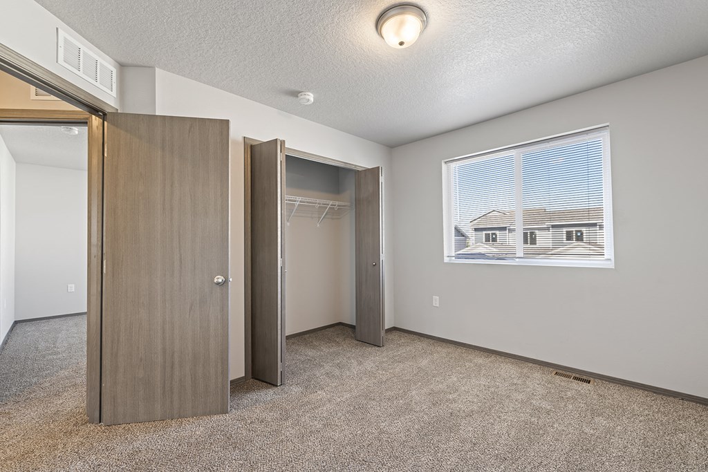 an empty room with a window and a closet