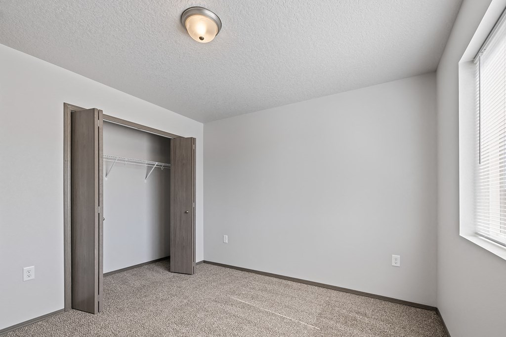 Bright, vacant bedroom with neutral walls and carpet flooring.