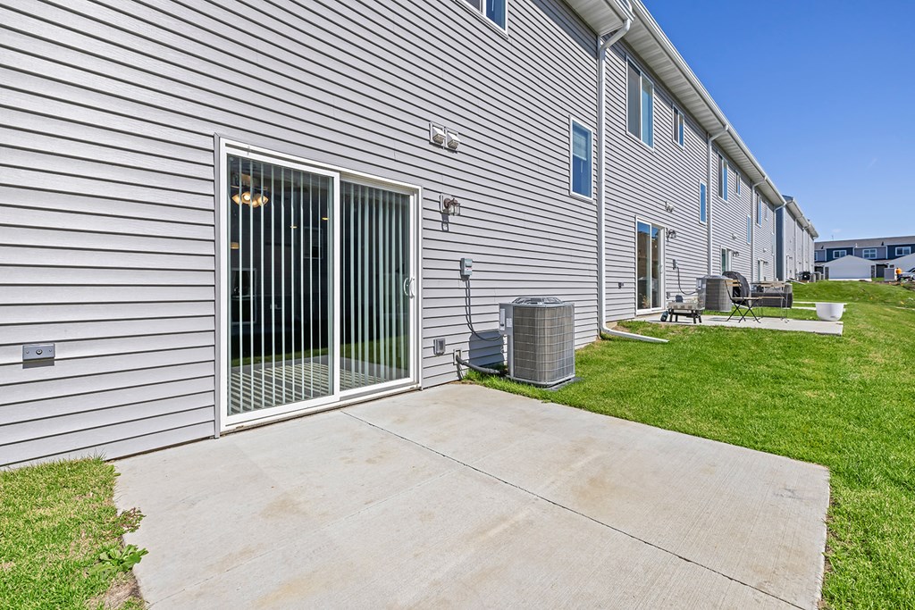 the yard of a white building with a patio and sliding glass doors
