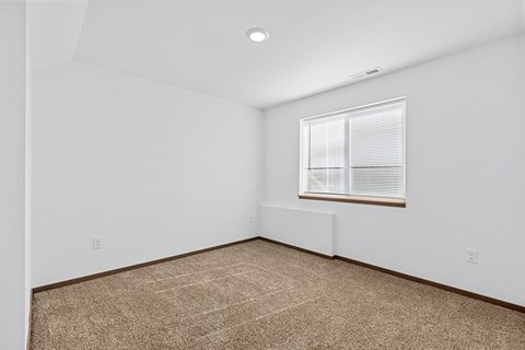 A room with a window and carpeted floor.