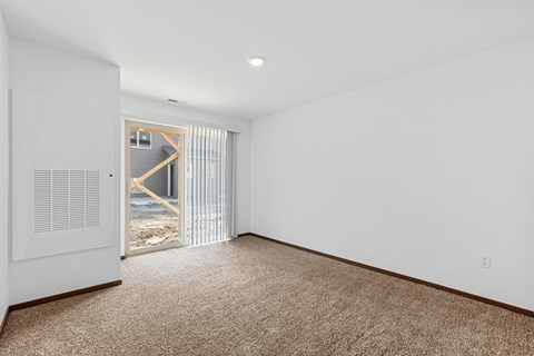A room with a carpeted floor and a window with blinds.