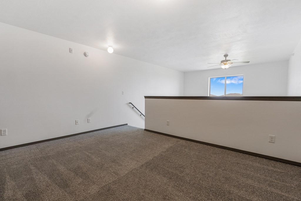 A room with a carpeted floor and a window with a view of the sky.
