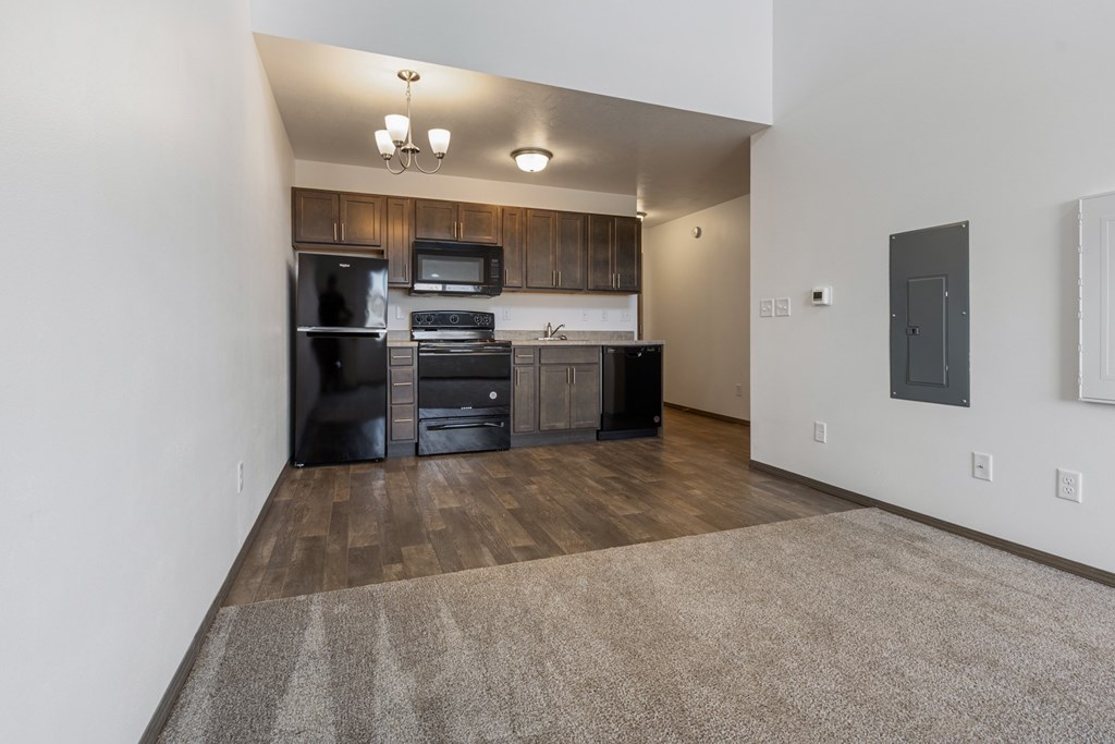 A kitchen with dark wood cabinets and black appliances.