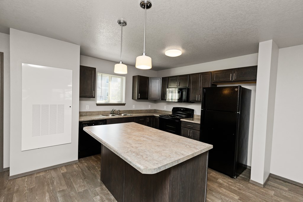A kitchen with a black refrigerator and a wooden island.