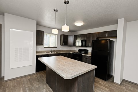 A kitchen with a black refrigerator and a wooden island.