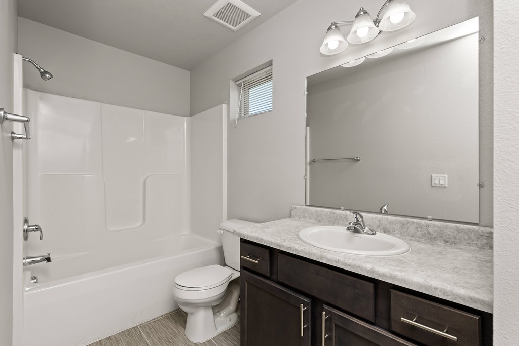 A white bathroom with a toilet, sink, and shower.