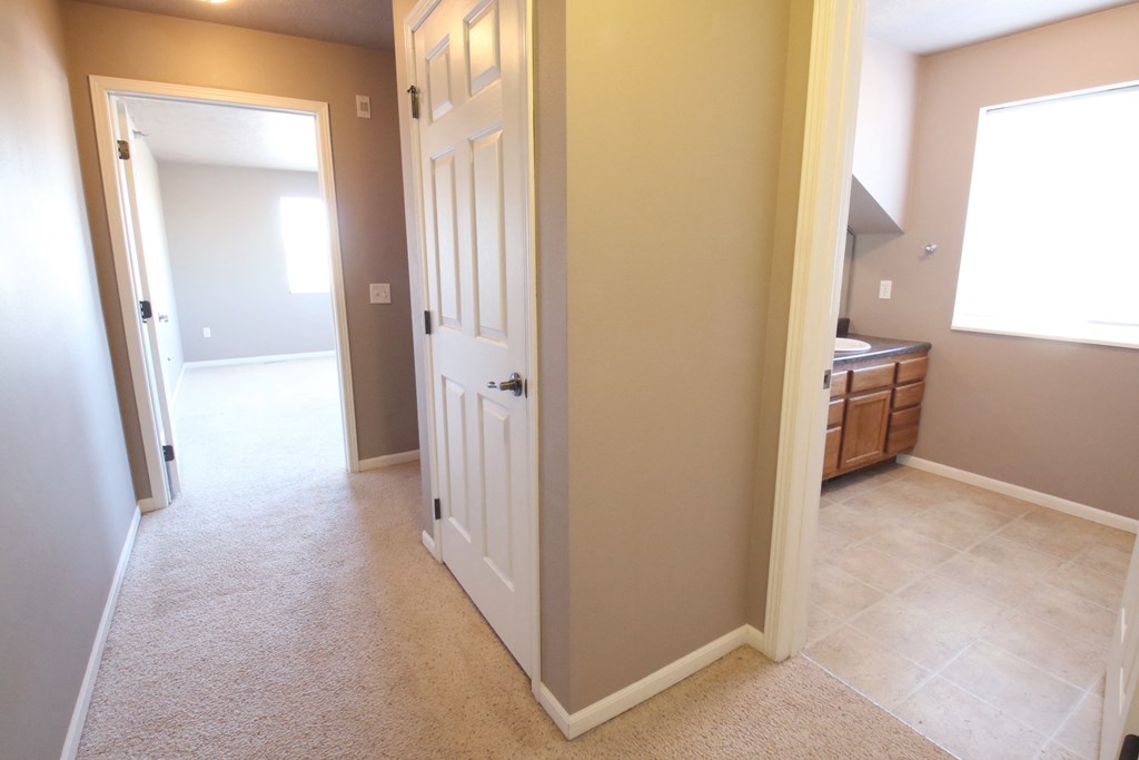 an open door leading into a bathroom and a hallway to a bedroom and a bathroom