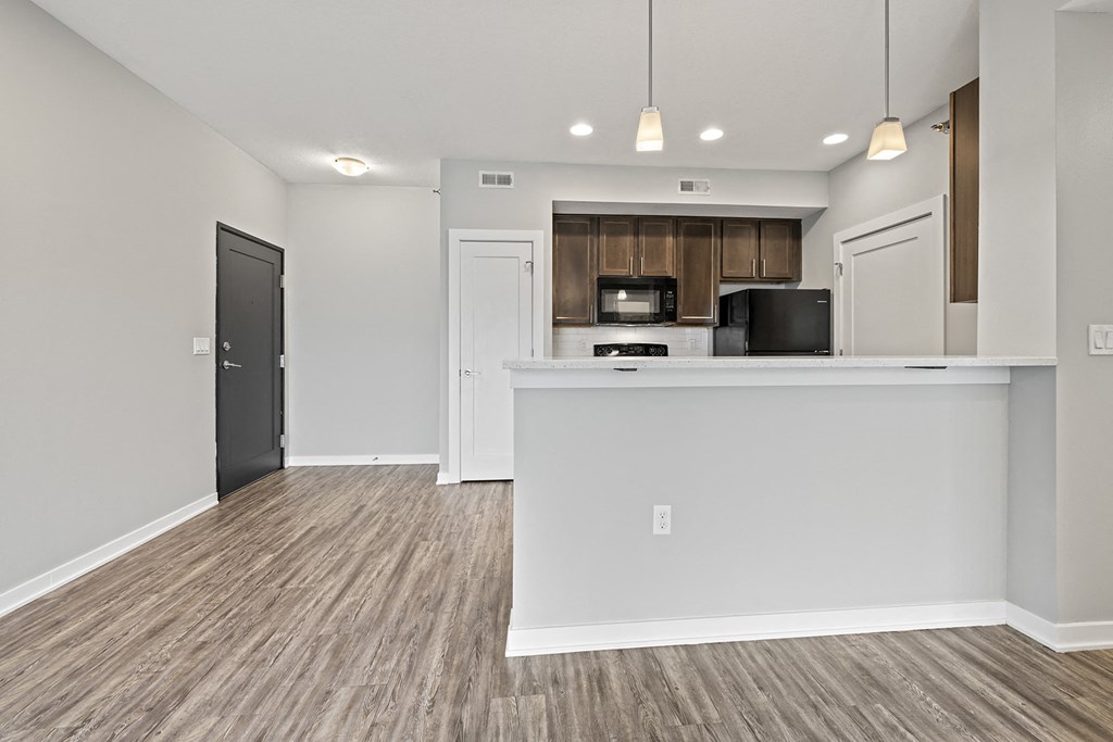 an empty kitchen and living room with a counter top and a refrigerator and a microwave