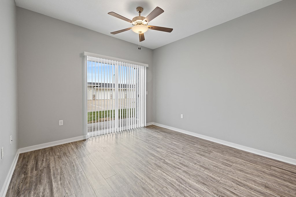 an empty living room with a ceiling fan and a window