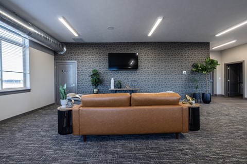 A living room with a brown sofa and a grey patterned wall.